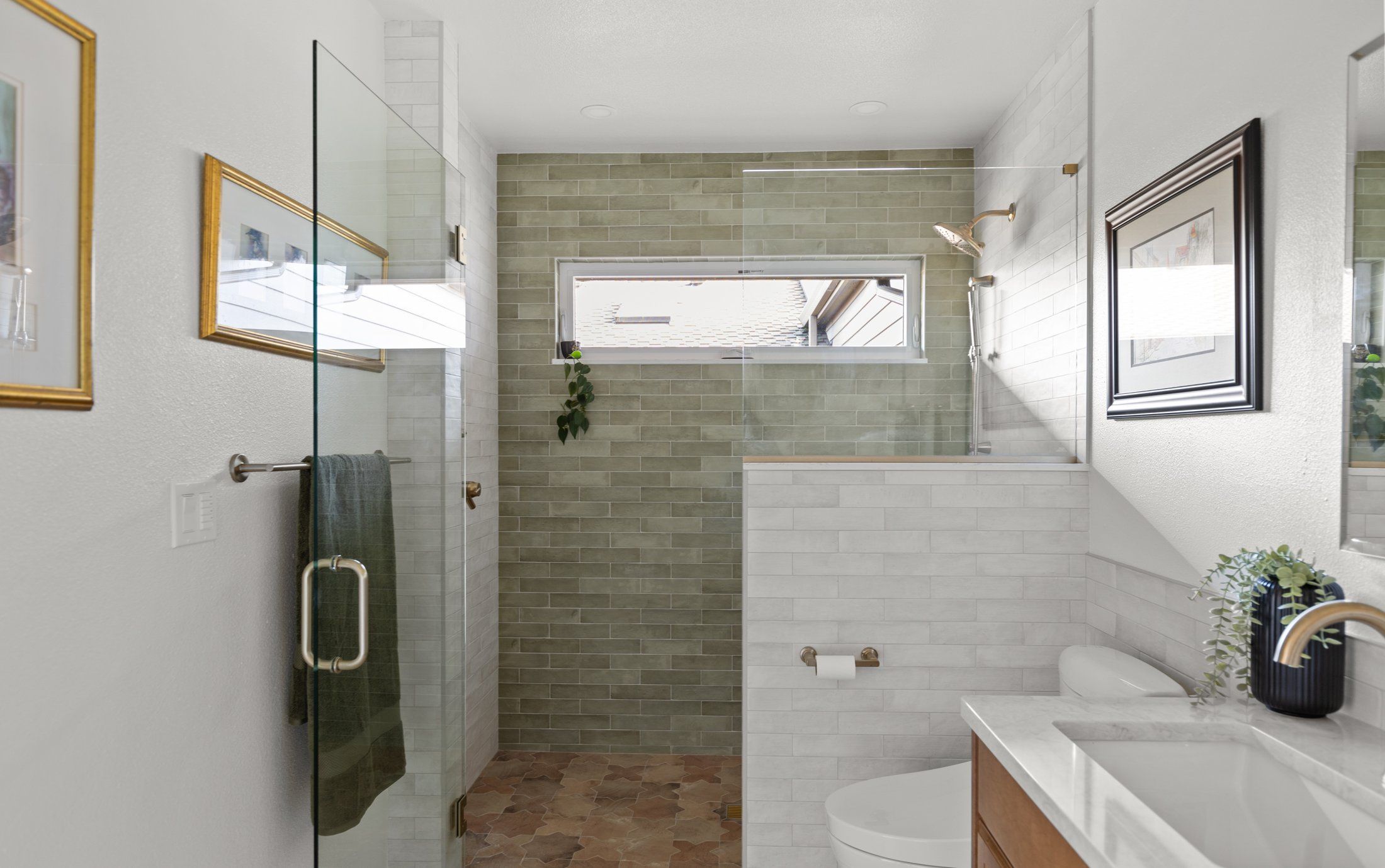 View into the remodeled bathroom through the doorway, showing the glass shower door and green tile shower