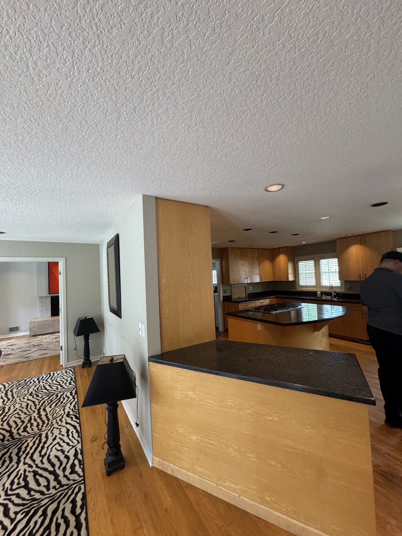 Before: dark granite peninsula and wood cabinets facing the dining area