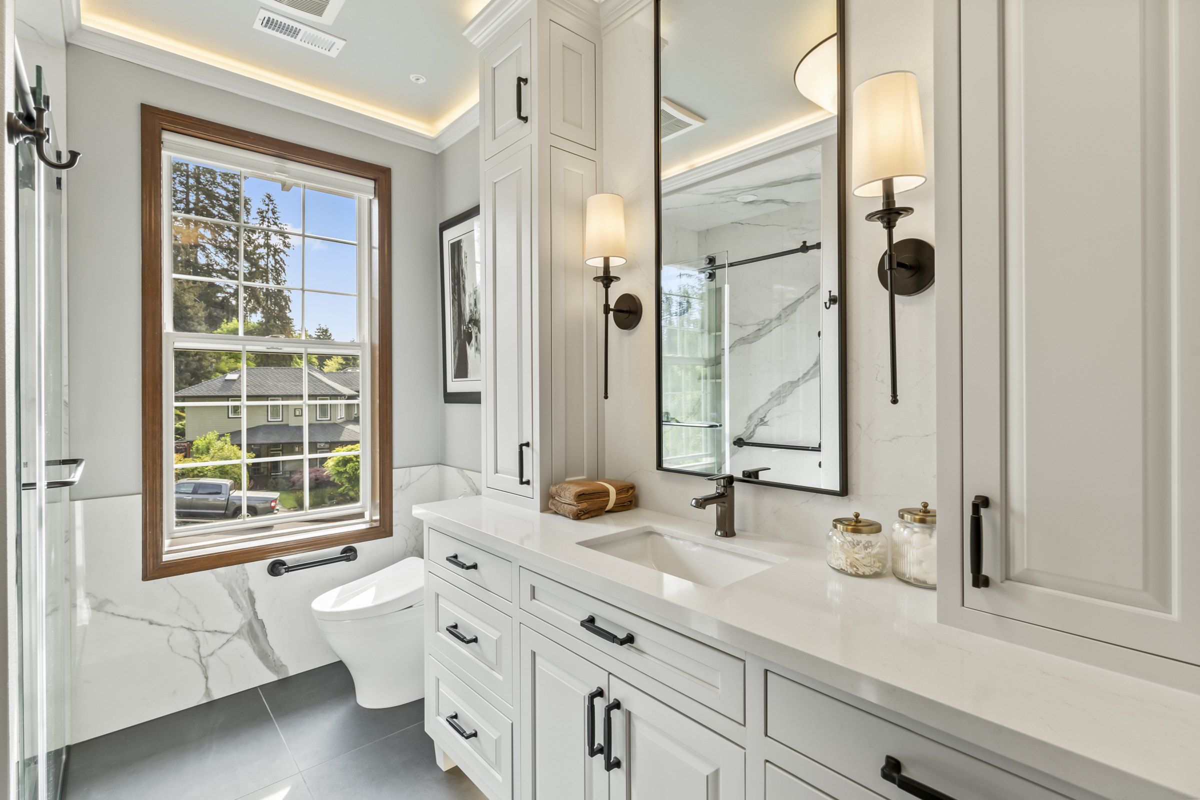 Bathroom with a white vanity, black-framed mirror, matte black fixtures and a window over the toilet