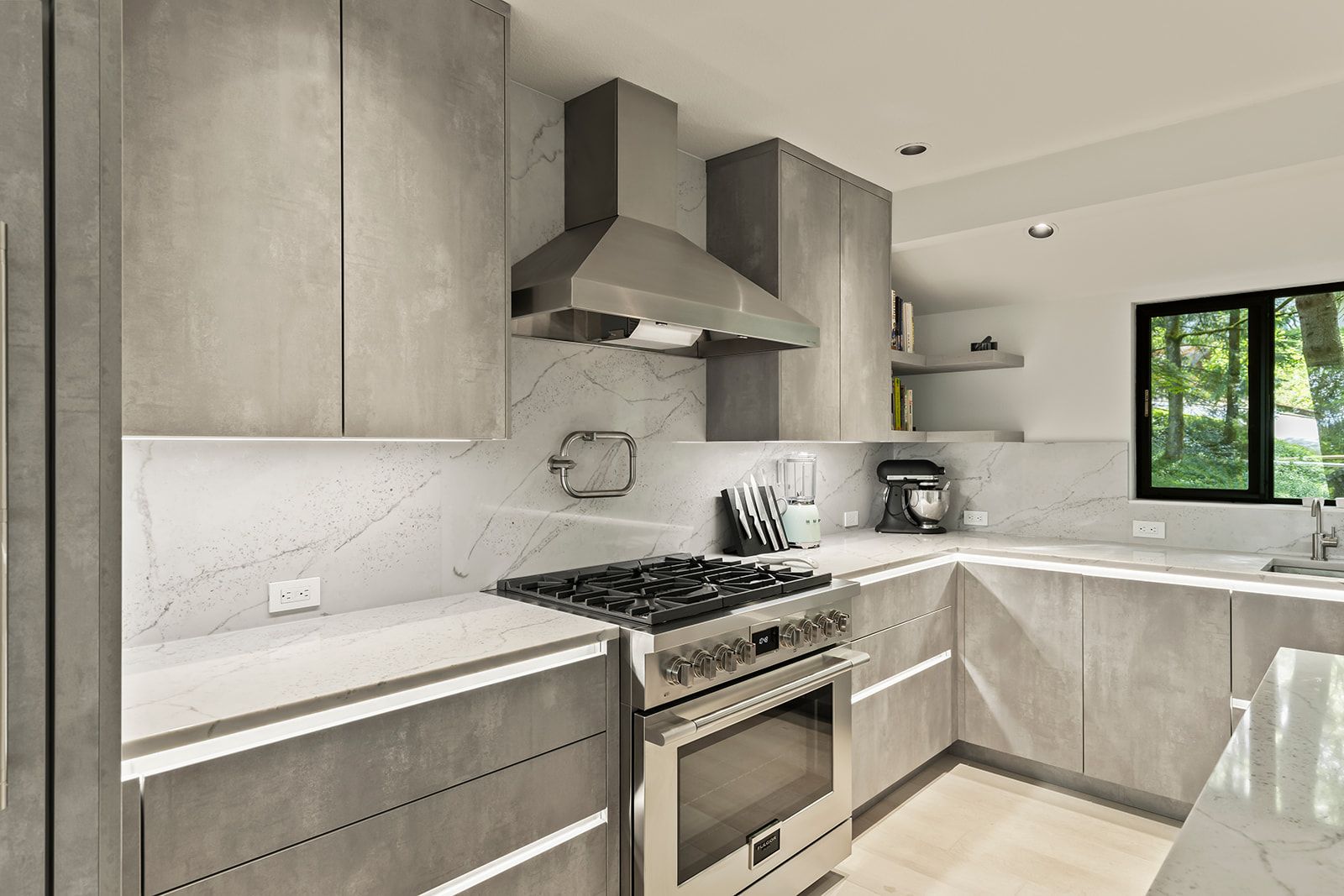 Kitchen range wall with gray cabinets, quartz backsplash, open shelving and a window over the counter