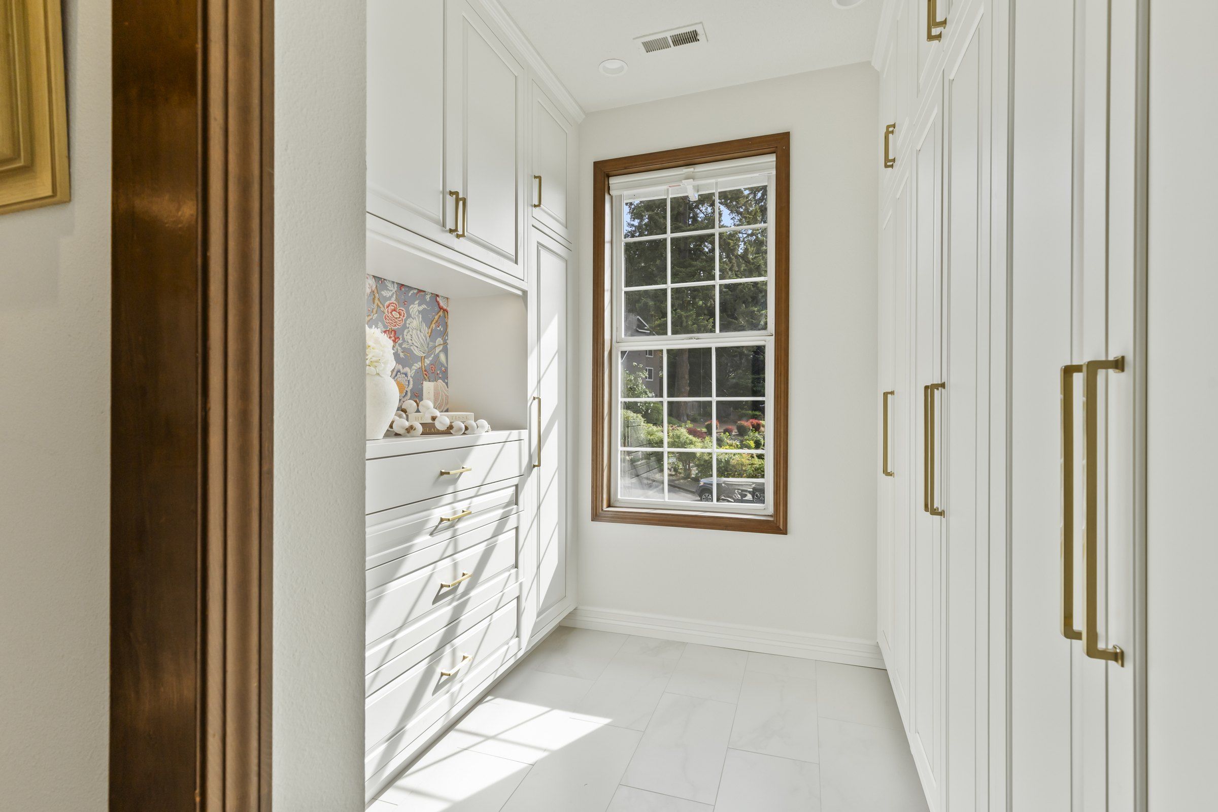 Linen closet with full-height cabinets and a window