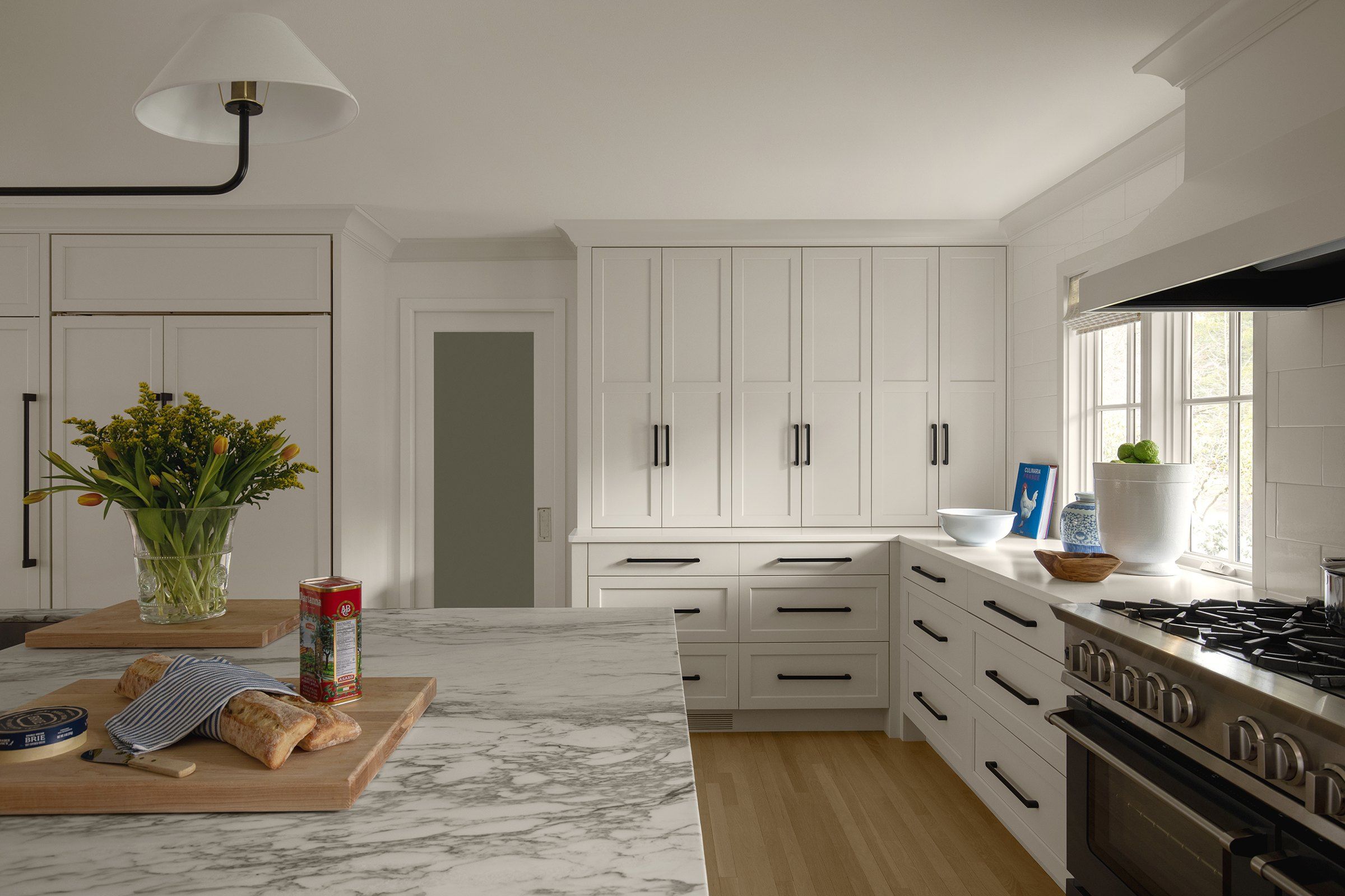 Honed marble island countertop in front of tall paneled cabinets
