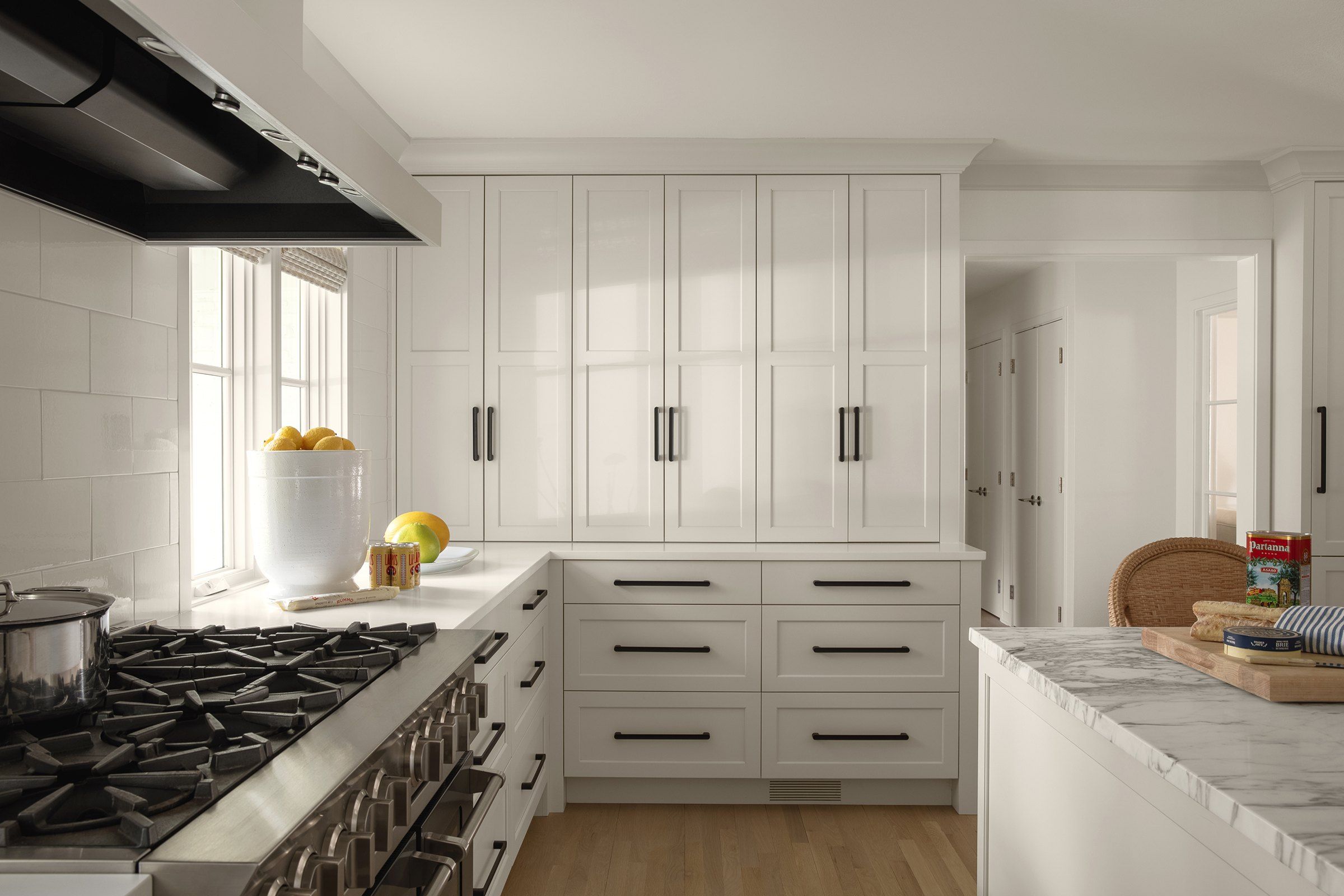 BlueStar range under a white hood with glossy white backsplash tile