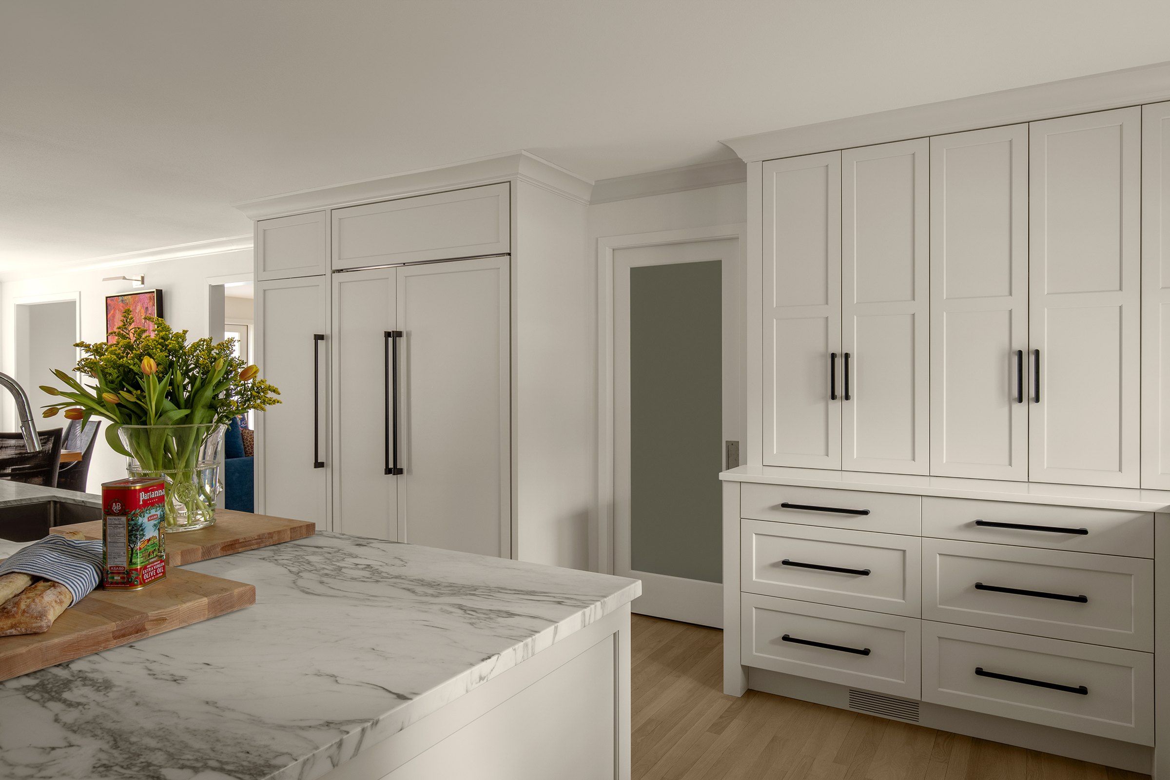 Wall of tall white cabinets beside an etched glass pocket door