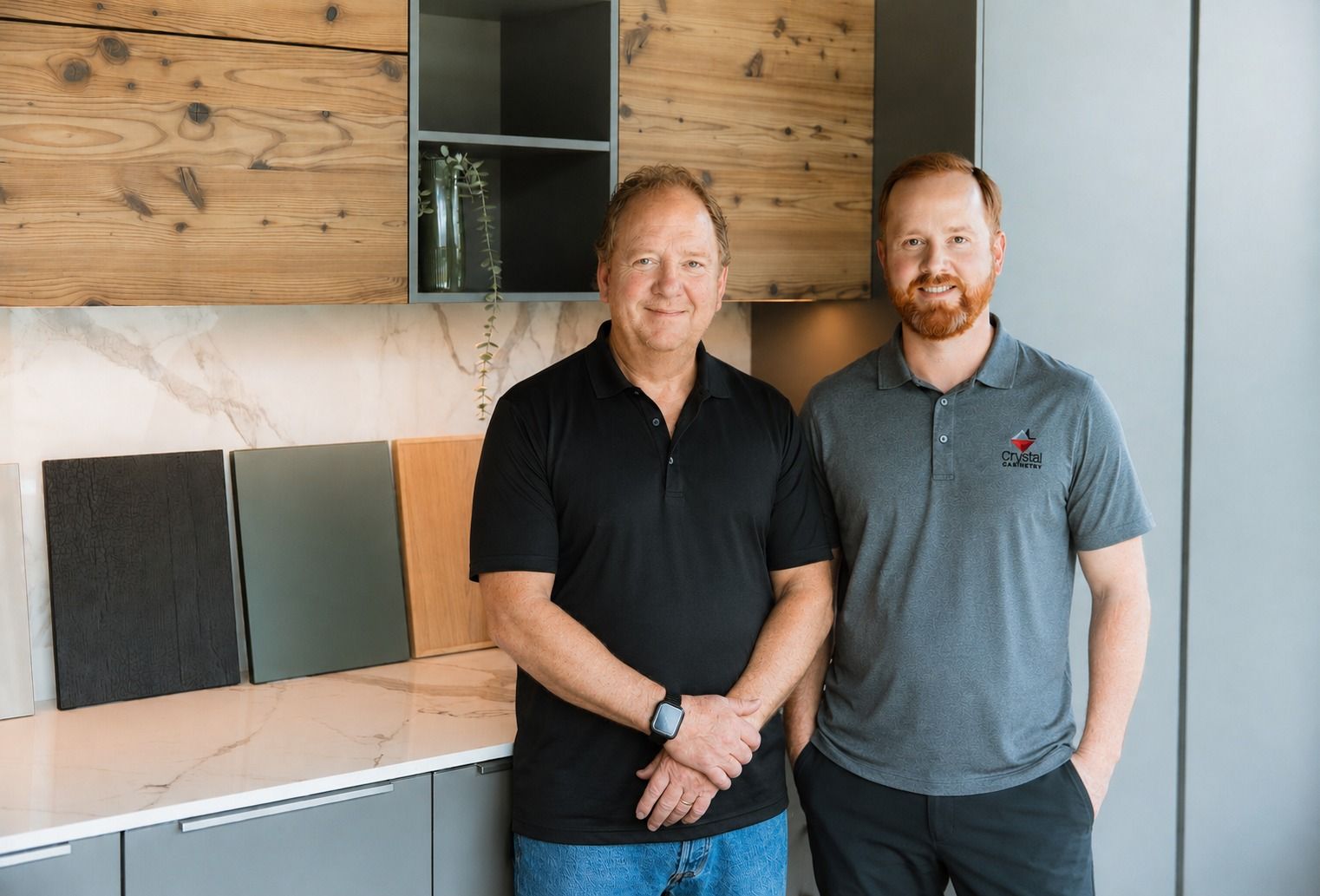 Two members of the Crystal Remodeling team standing in the design showroom in front of cabinet and door samples