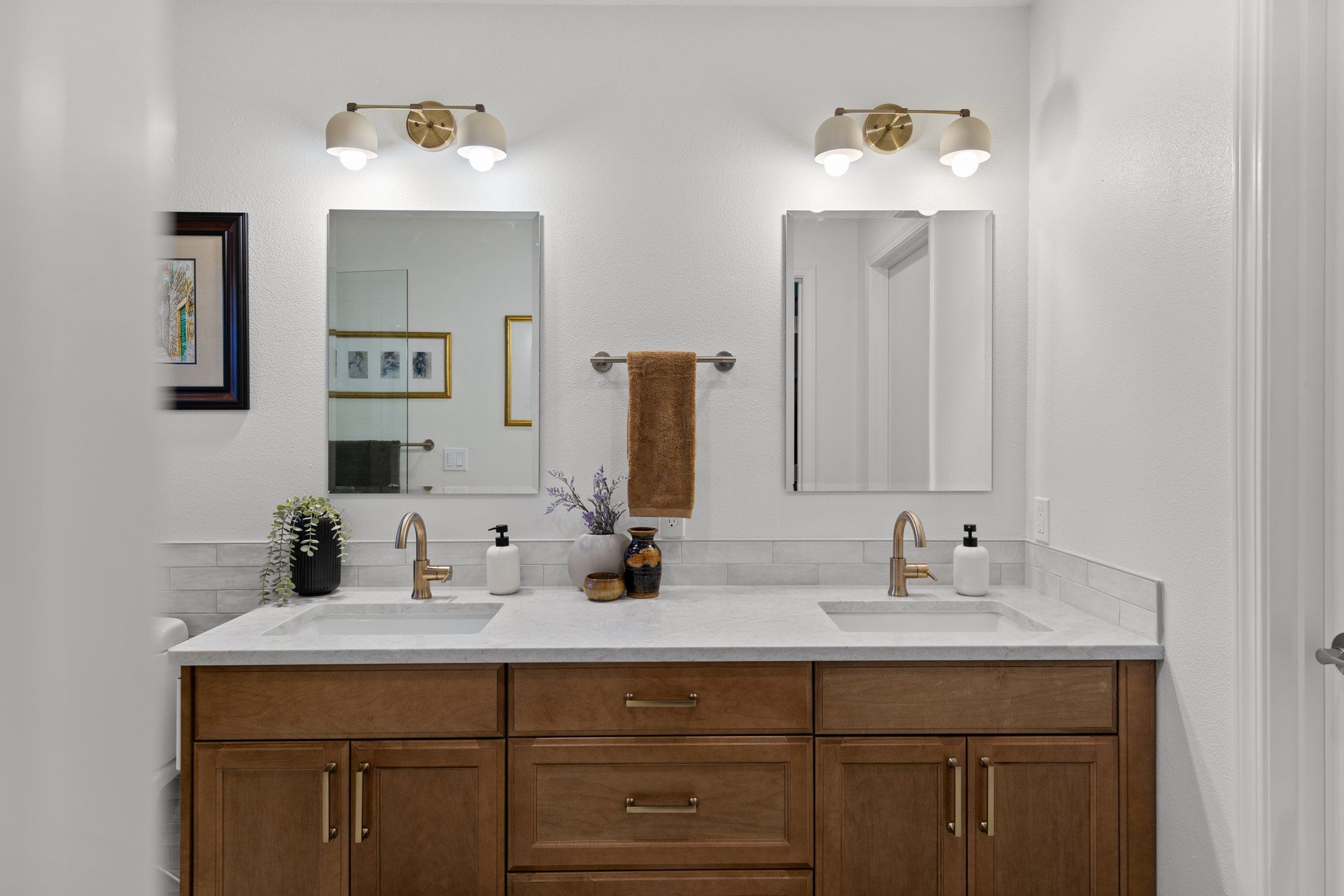 Double vanity in cinnamon-stained maple with white quartz top, brass faucets, two mirrors and brass light fixtures